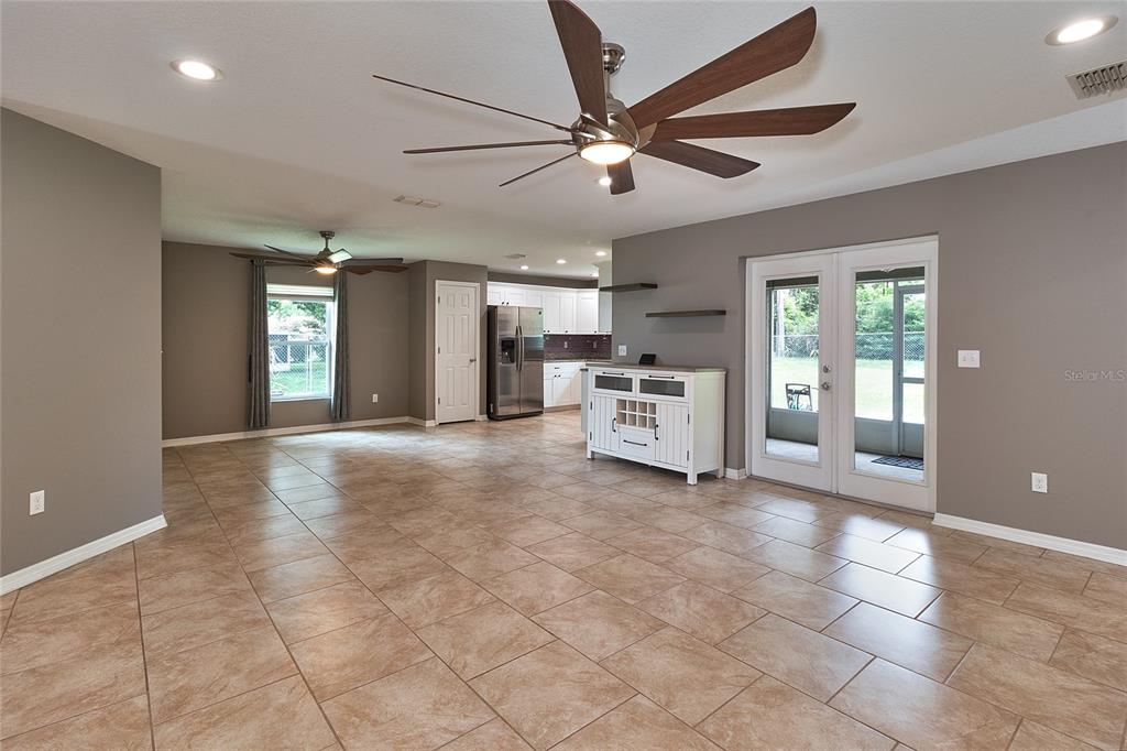 An open-concept living area features tile flooring, a ceiling fan, and glass doors to a patio — 5130 20TH STREET, ZEPHYRHILLS, FL