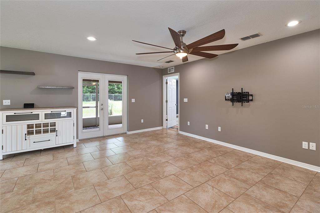 A living room features tile flooring, a ceiling fan, a wall-mounted TV bracket, and French doors — 5130 20TH STREET, ZEPHYRHILLS, FL