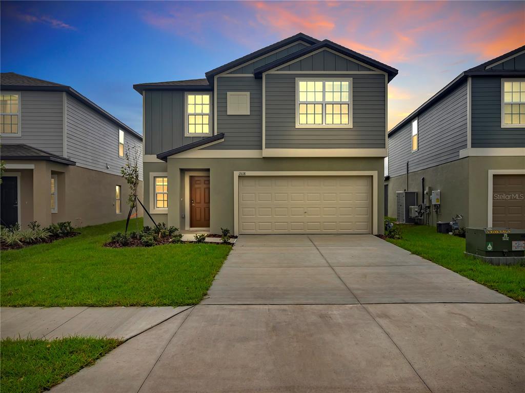 A two-story suburban house features a beige garage, gray siding, and a concrete driveway — 13118 EMPRESS JEWEL TRAIL, PARRISH, FL
