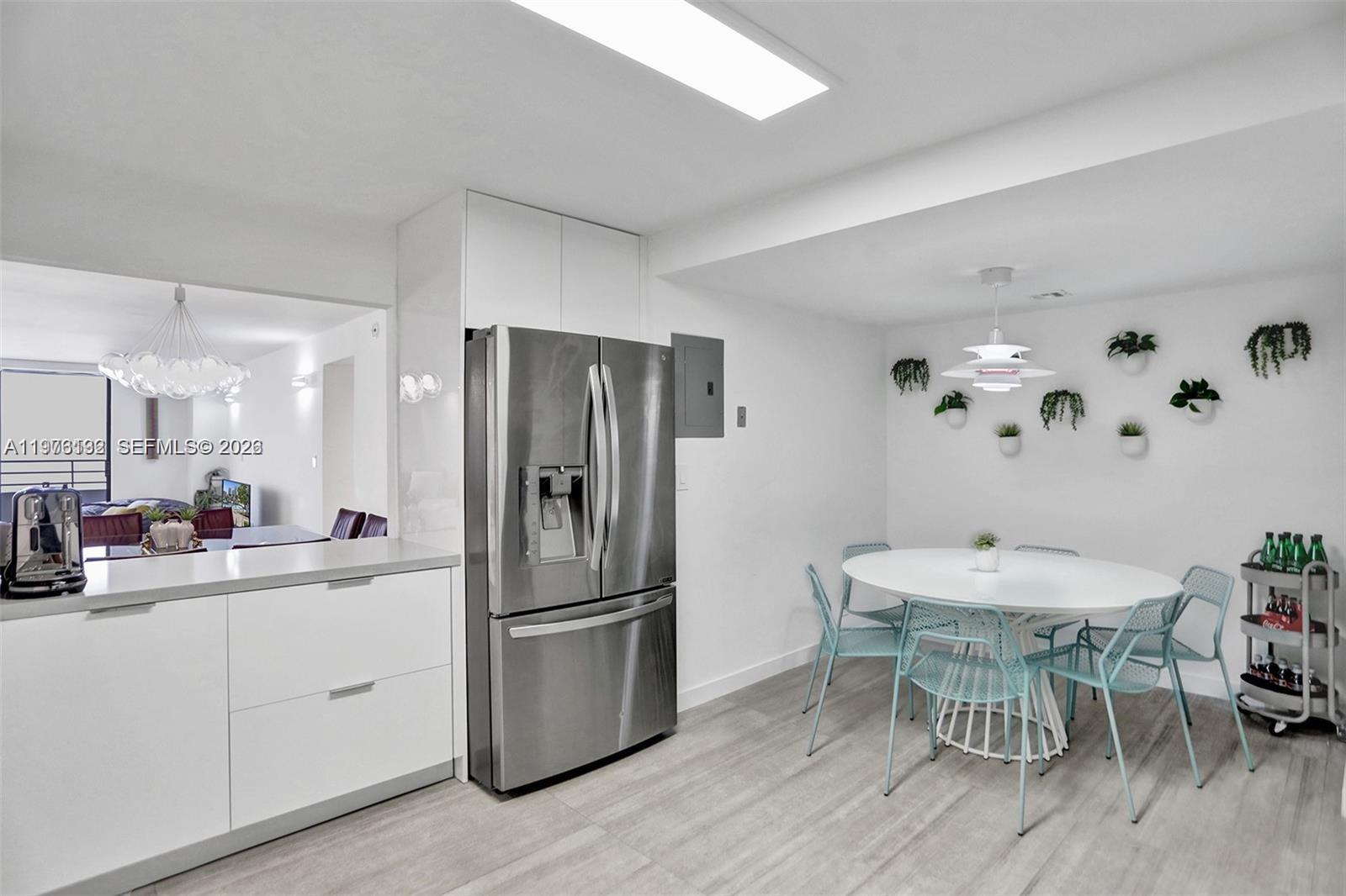 A modern kitchen and dining area feature white cabinetry, stainless steel appliances, and light flooring — 2500 Parkview Dr # 1912, Hallandale Beach FL 33009, HALLANDALE BEACH, FL