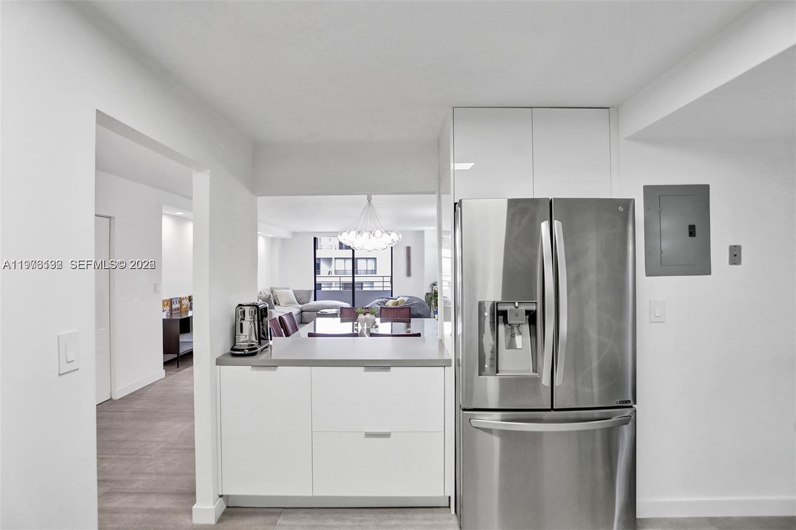 A modern kitchen features white cabinetry, a stainless steel refrigerator, and a gray countertop — 2500 Parkview Dr # 1912, Hallandale Beach FL 33009, HALLANDALE BEACH, FL