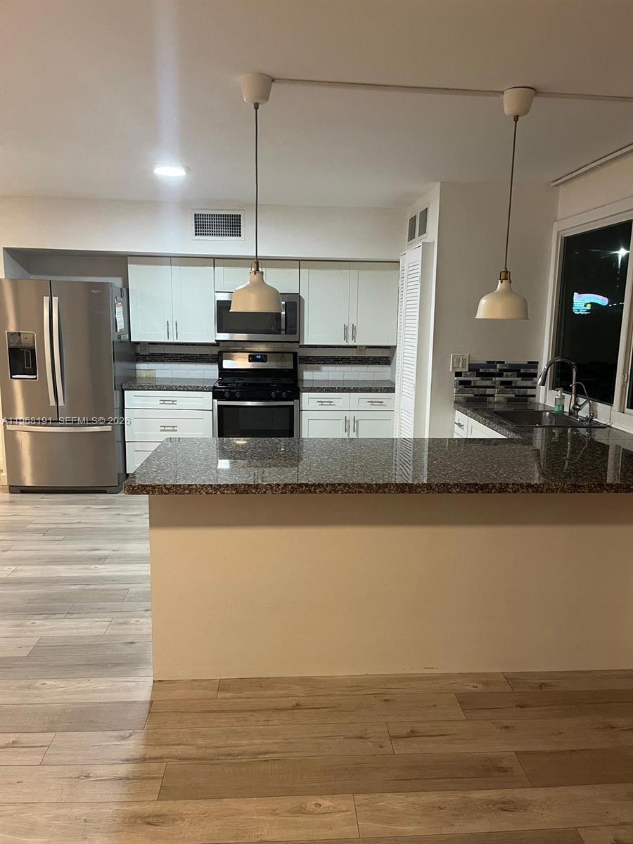 A kitchen features white cabinets, granite countertops, stainless steel appliances, and two pendant lights — 7133 SW 109th Ct, Miami FL 33173, MIAMI, FL