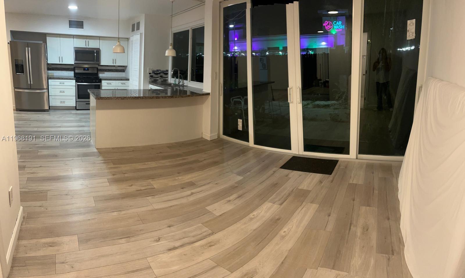 A kitchen with stainless steel appliances and a breakfast bar opens to a living area — 7133 SW 109th Ct, Miami FL 33173, MIAMI, FL