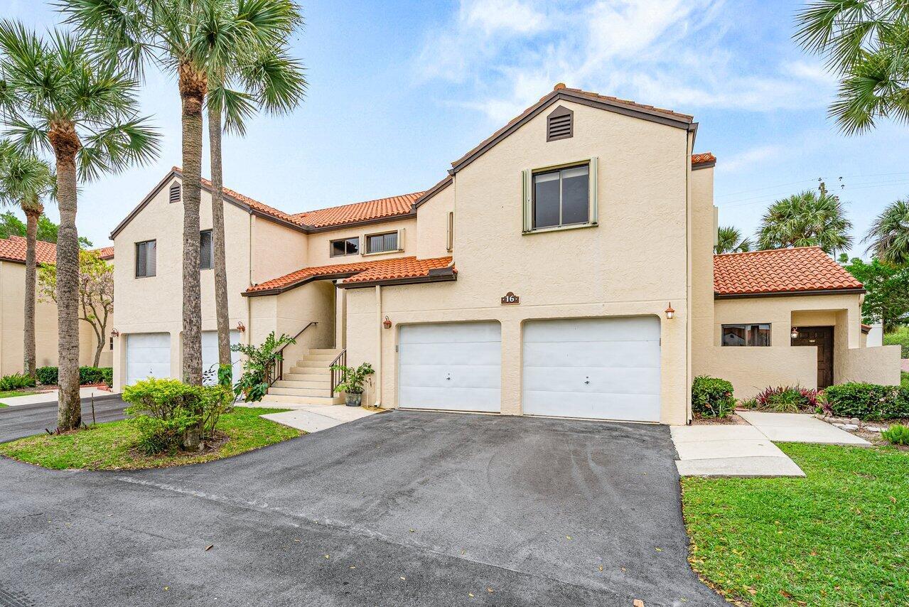 A two-story stucco townhouse with a two-car garage, tile roof, and palm trees — 16 Via De Casas Sur # 204, Boynton Beach FL 33426, BOYNTON BEACH, FL