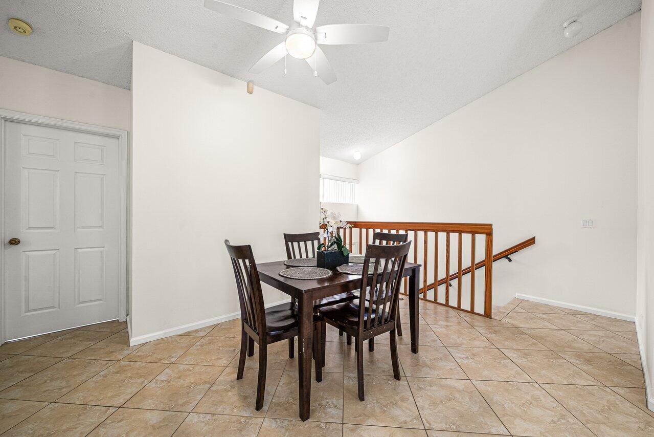 A dining area features a dark wood table, four chairs, and tile flooring — 16 Via De Casas Sur # 204, Boynton Beach FL 33426, BOYNTON BEACH, FL