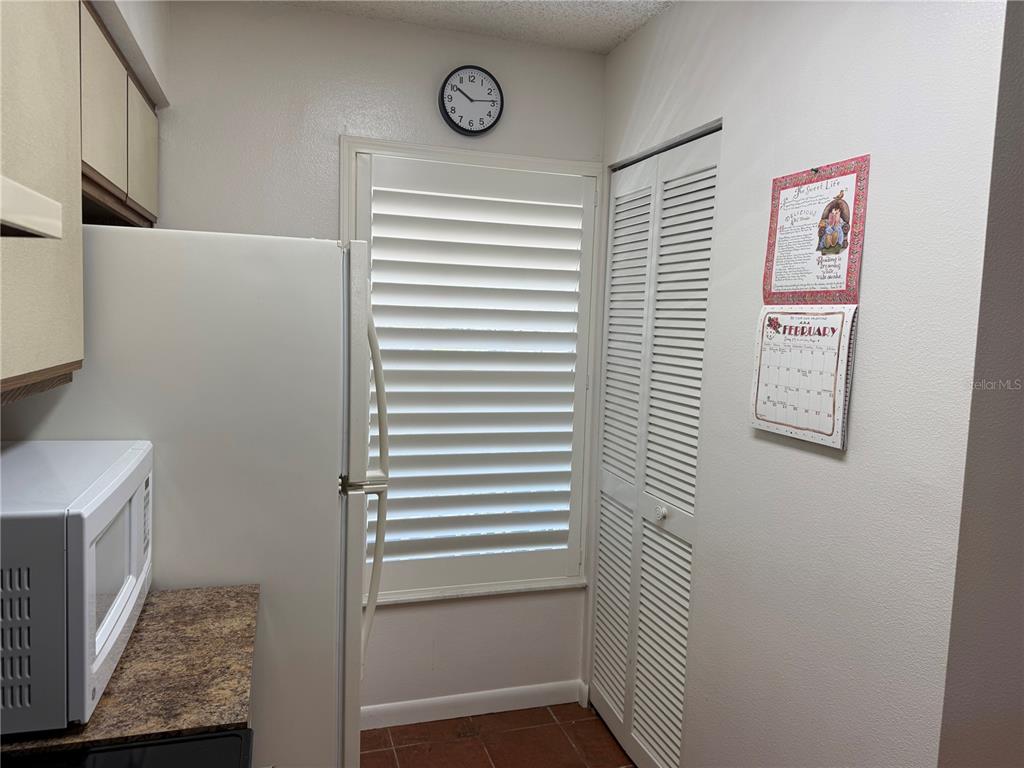 A kitchen features a white refrigerator, a microwave, a window with shutters, and a calendar — 6519 SPRING FLOWER DRIVE UNIT 22, NEW PORT RICHEY, FL