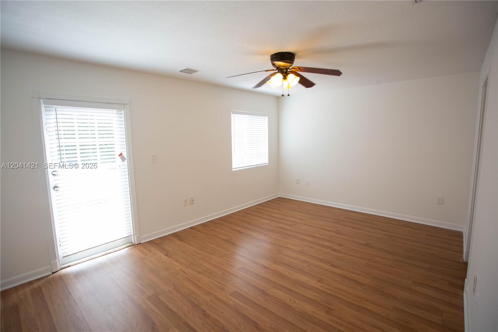 An empty room features light wood-look flooring, white walls, a ceiling fan, and a glass door — 2919 Virginia St, Miami FL 33133, MIAMI, FL