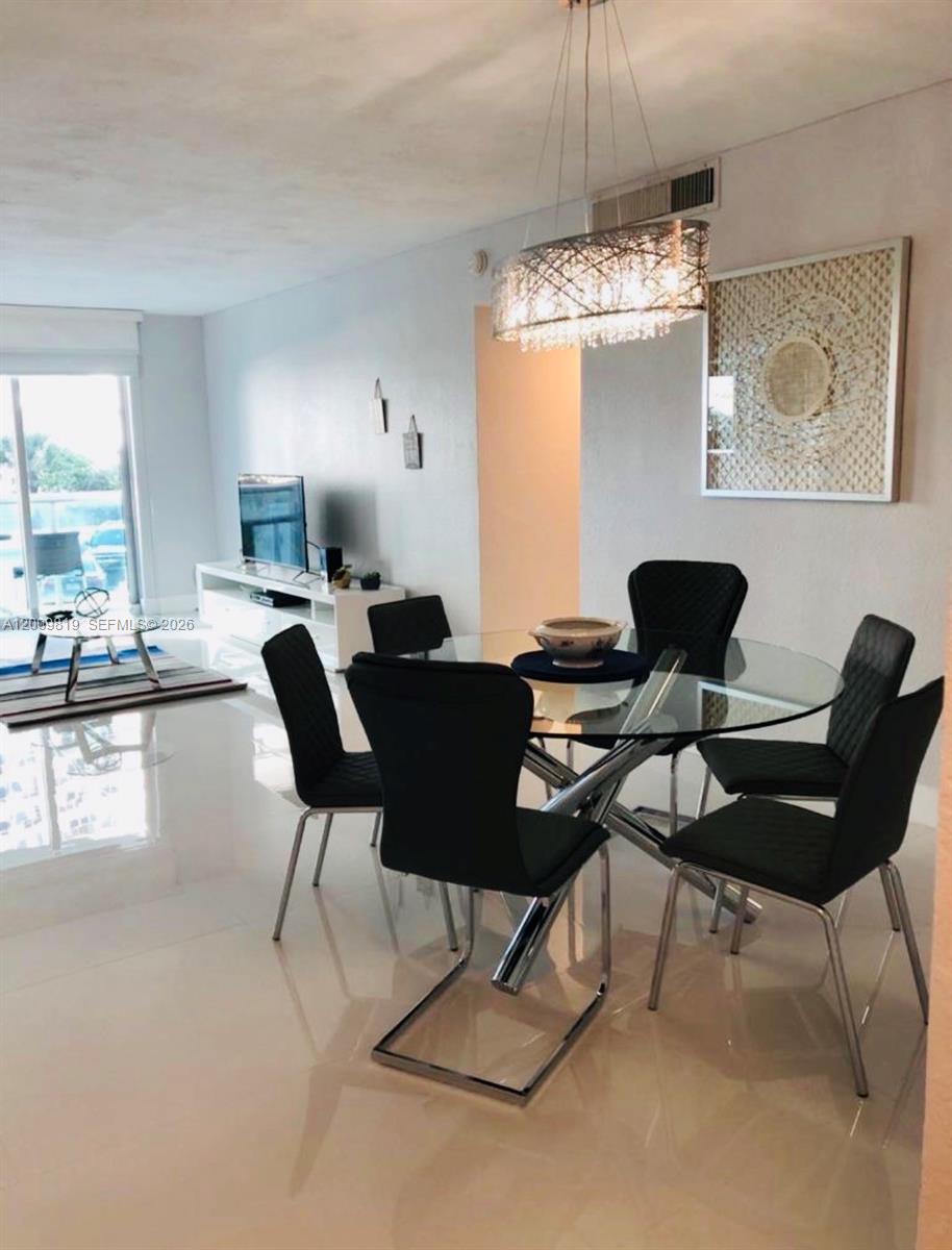 A dining area features a glass-topped table with black chairs under a modern chandelier — 3801 S Ocean Dr # 2B, Hollywood FL 33019, HOLLYWOOD, FL