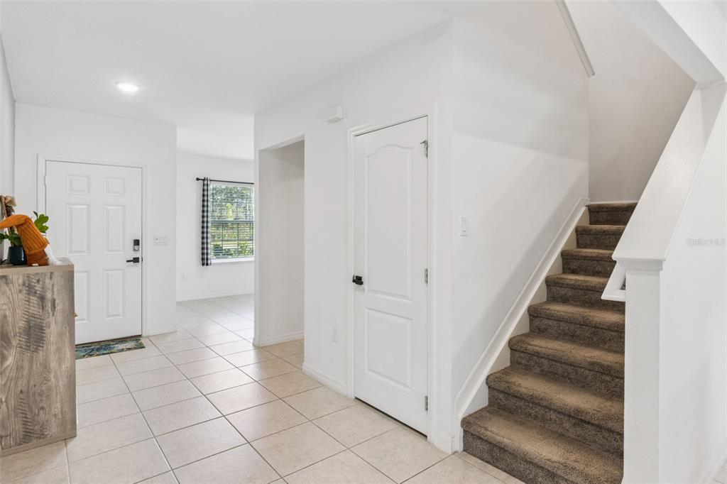 An entryway features tile flooring, a carpeted staircase, and a white door leading inside — 3681 MAGNOLIA DRIVE, INDIAN LAKE ESTATES, FL