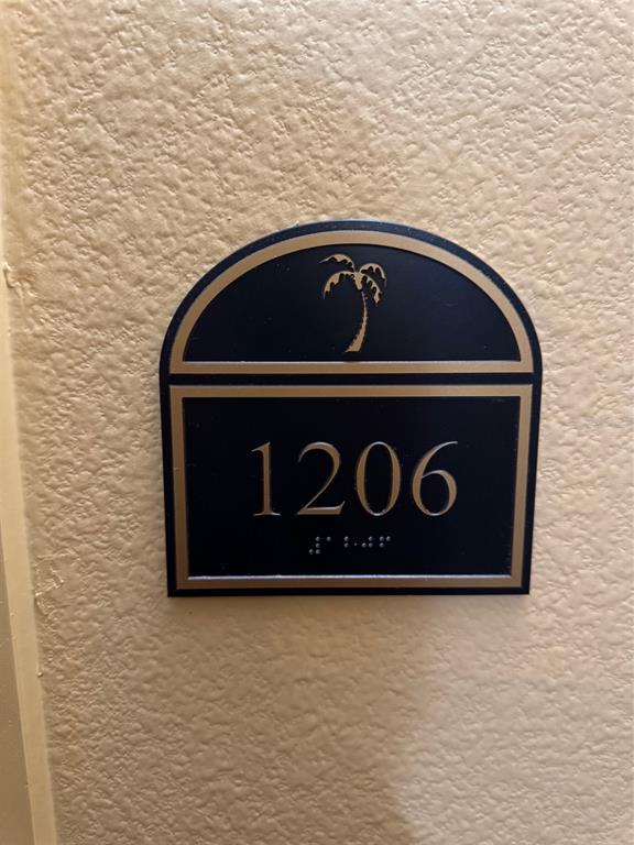 A dark blue, arched room number sign with a palm tree icon and braille text — 8112 POINCIANA BOULEVARD UNIT 1206, ORLANDO, FL