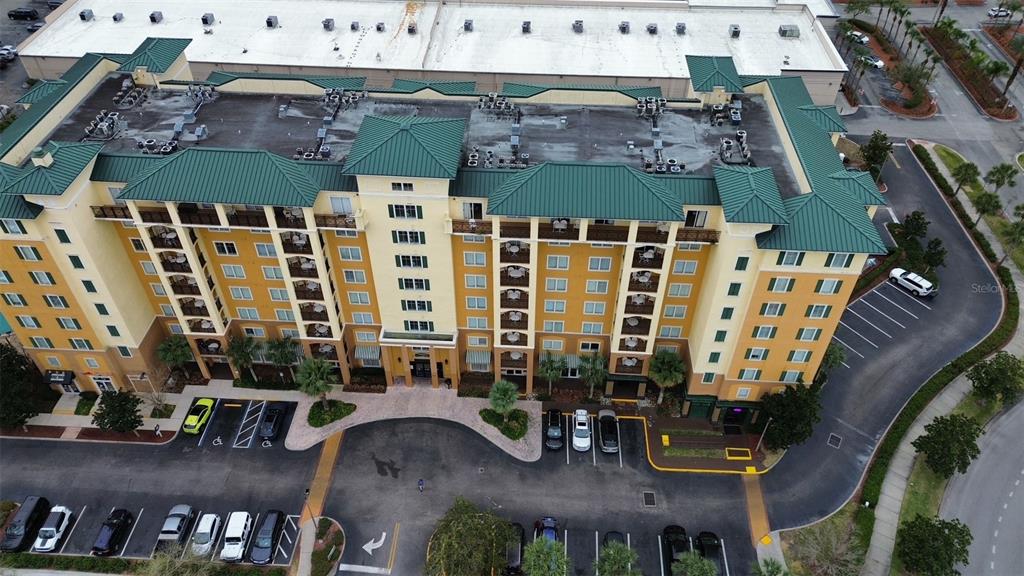 An aerial view shows a multi-story hotel building with a green roof and parking lot — 8112 POINCIANA BOULEVARD UNIT 1206, ORLANDO, FL