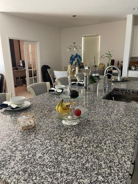 A kitchen island with a granite countertop and a tiered fruit stand sits before a dining area — 5014 ROYAL POINT AVENUE, KISSIMMEE, FL