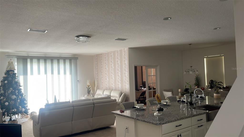 An open-concept living room and kitchen feature a granite island, white sofa, and Christmas tree — 5014 ROYAL POINT AVENUE, KISSIMMEE, FL