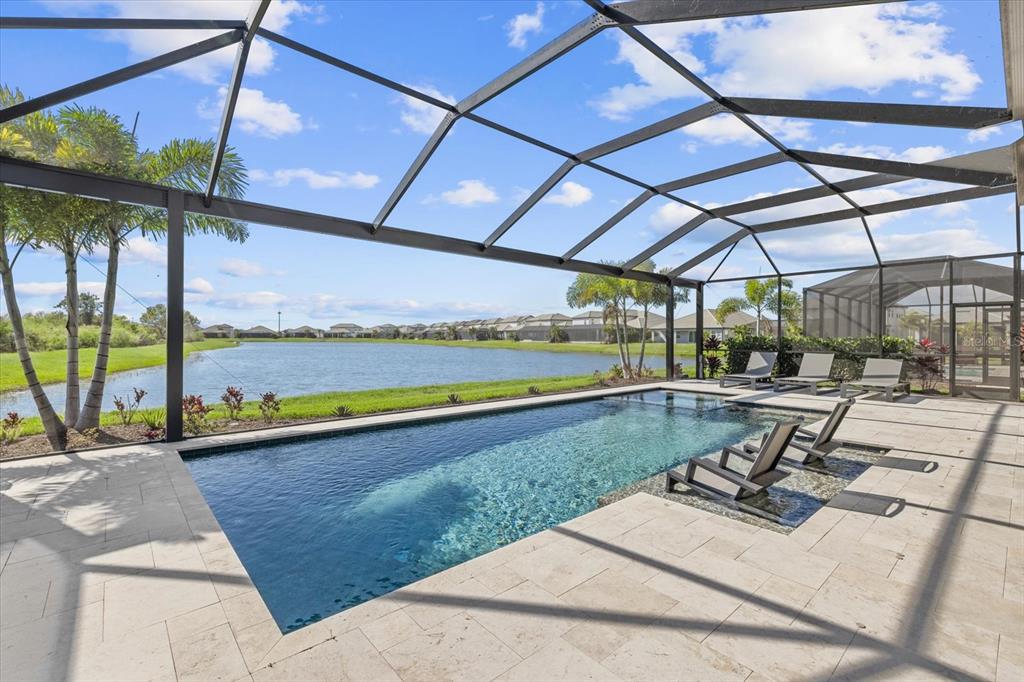A screened-in pool patio features a rectangular swimming pool with a tanning ledge and lake view — 4618 SWEET RETREAT RUN, LAKEWOOD RANCH, FL