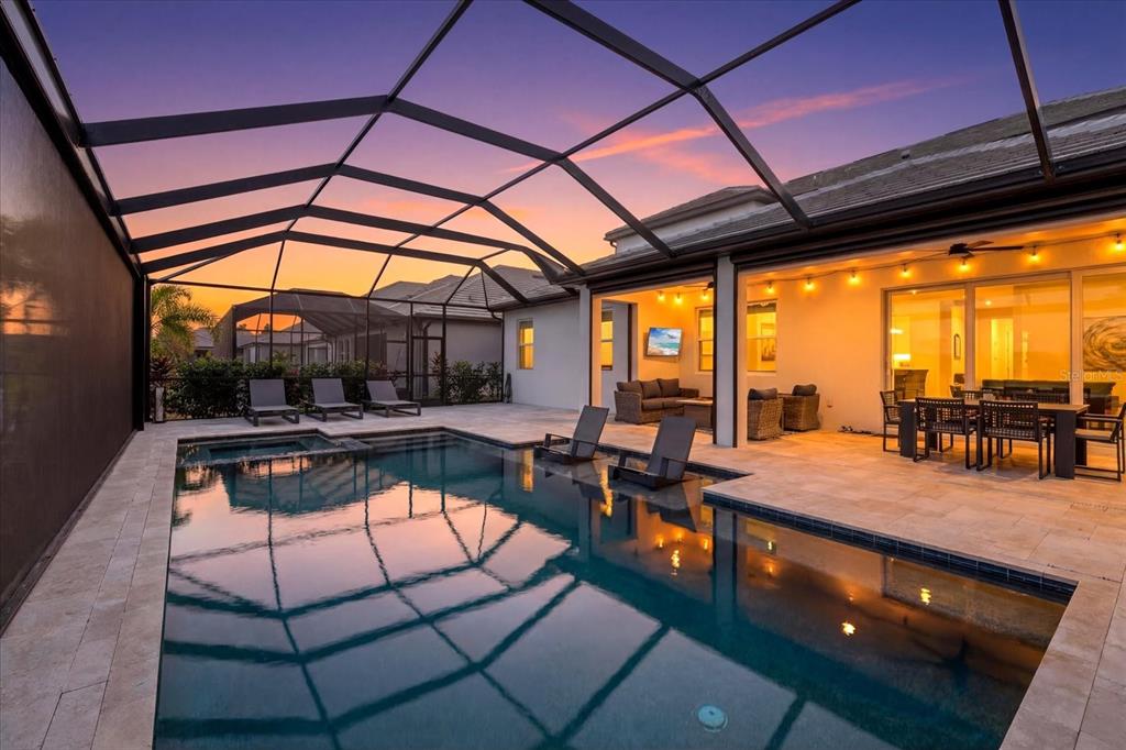 A screened-in patio features a swimming pool, lounge chairs, and an outdoor dining area at sunset — 4618 SWEET RETREAT RUN, LAKEWOOD RANCH, FL