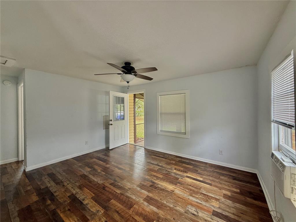 An empty room features wood-look flooring, a ceiling fan, and a door leading outside — 7581 S MYERS POINT, FLORAL CITY, FL