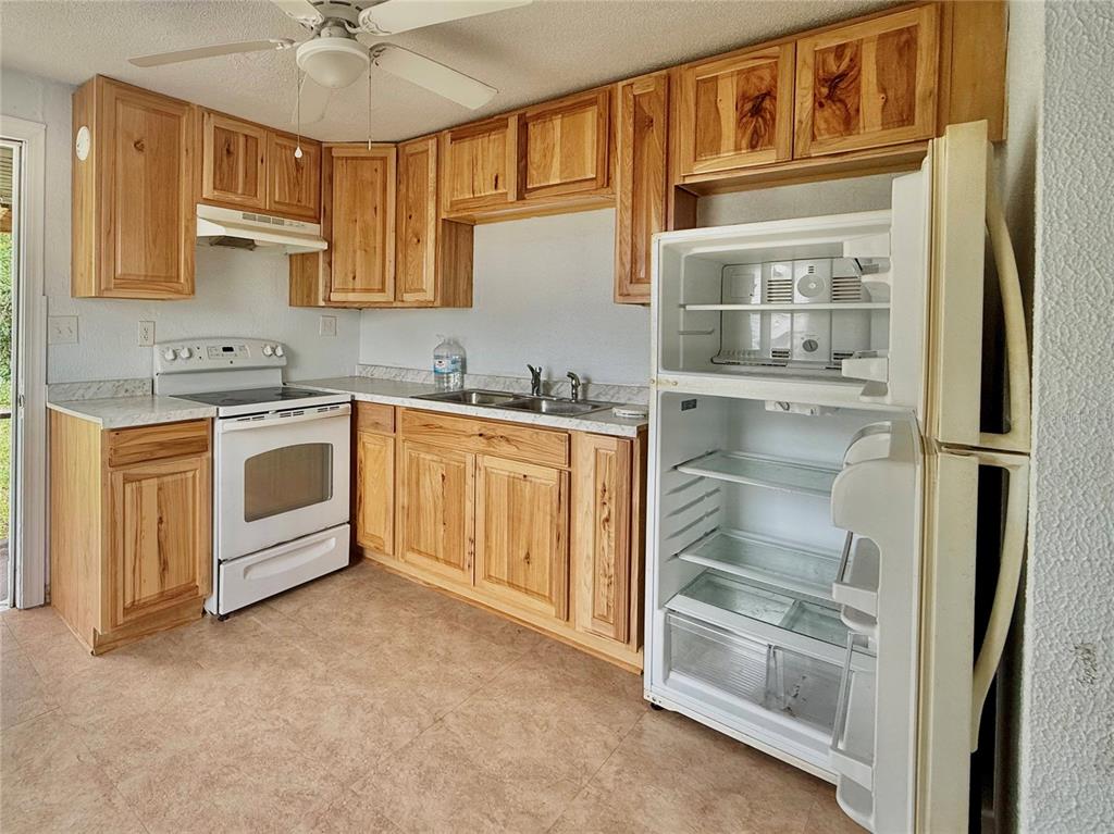 A kitchen features light wood cabinets, white appliances, a double sink, and tiled flooring — 7581 S MYERS POINT, FLORAL CITY, FL
