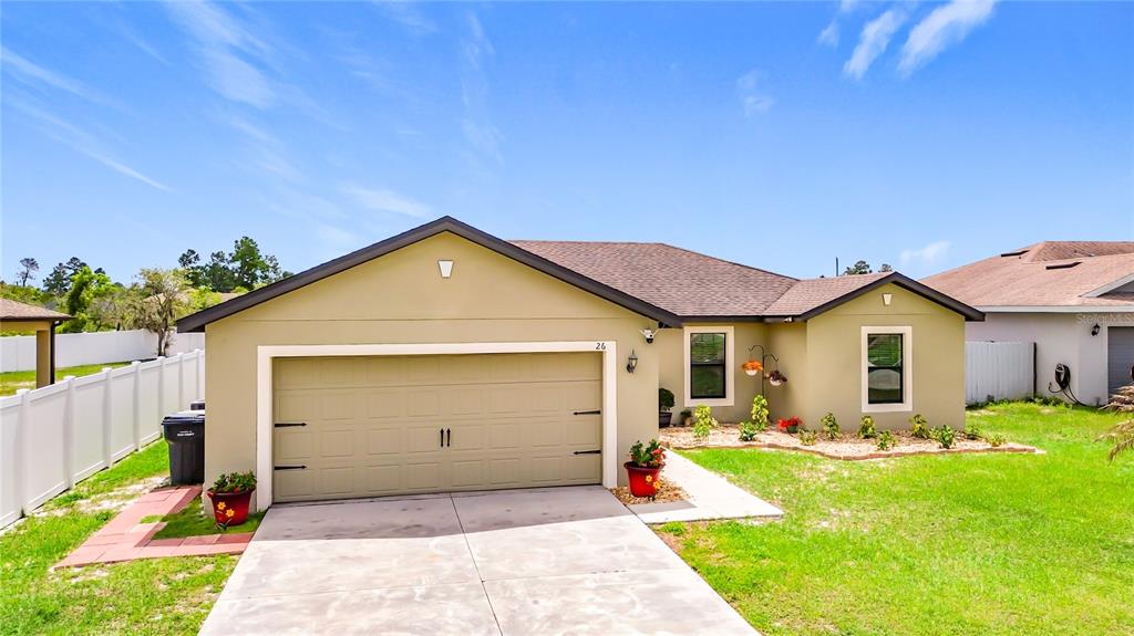 A single-story house with a tan exterior, a two-car garage, and a front lawn — 26 ORCHID COURT, KISSIMMEE, FL