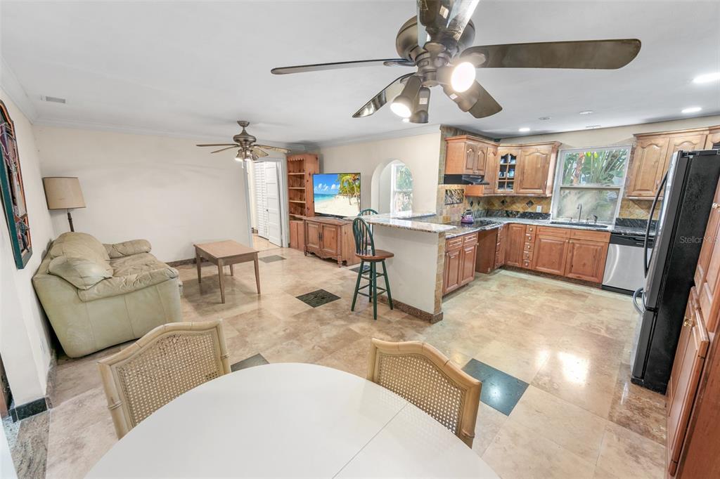 An open-concept kitchen and living area features tile flooring, wood cabinetry, and a ceiling fan — 332 FLETCHER AVENUE, DAYTONA BEACH, FL