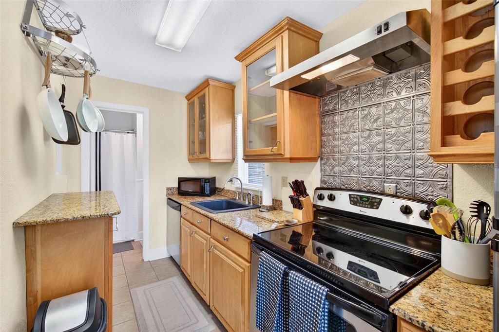 A kitchen with light wood cabinets, granite countertops, a metal backsplash, and stainless steel appliances — 509 29TH AVENUE S UNIT C, ST PETERSBURG, FL