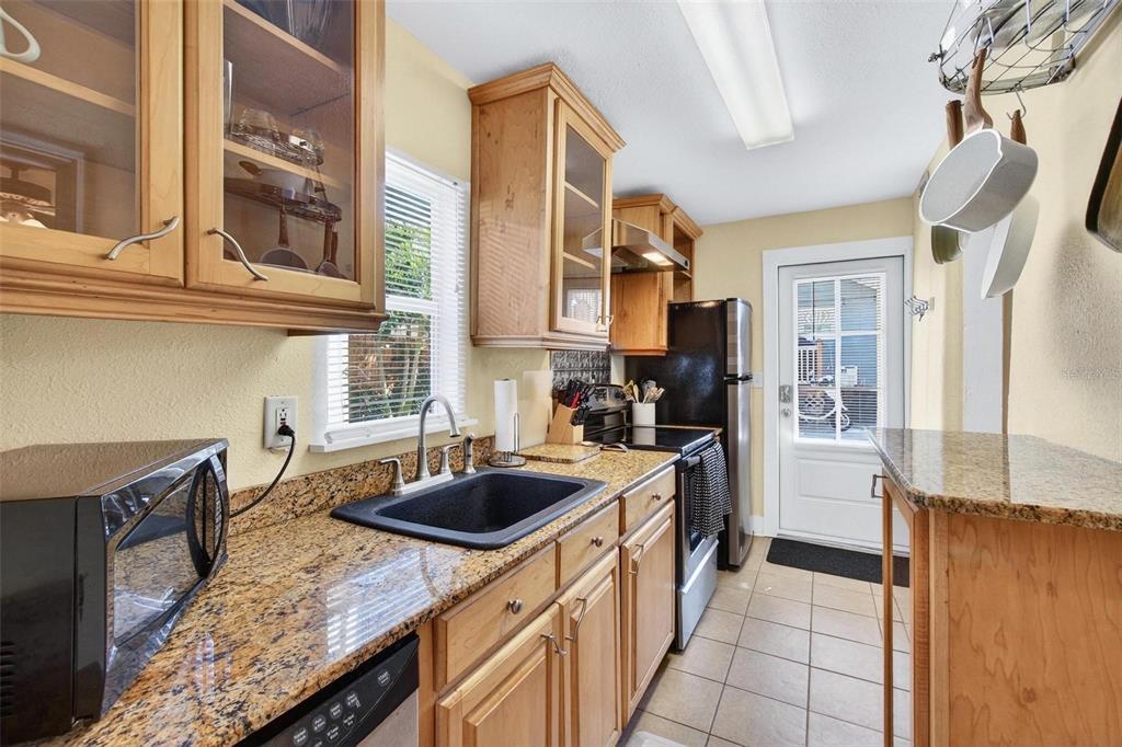 A kitchen with light wood cabinets, granite countertops, a black sink, and a black microwave — 509 29TH AVENUE S UNIT C, ST PETERSBURG, FL