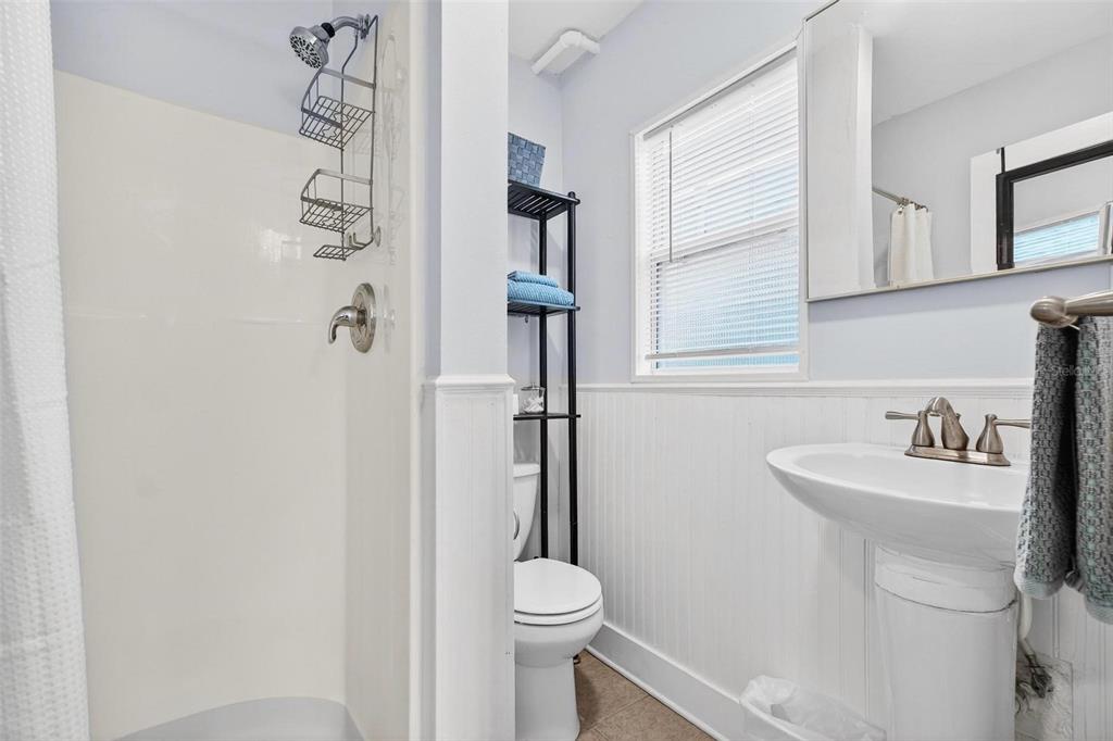 A bathroom features a white pedestal sink, a toilet, and a walk-in shower stall — 509 29TH AVENUE S UNIT C, ST PETERSBURG, FL
