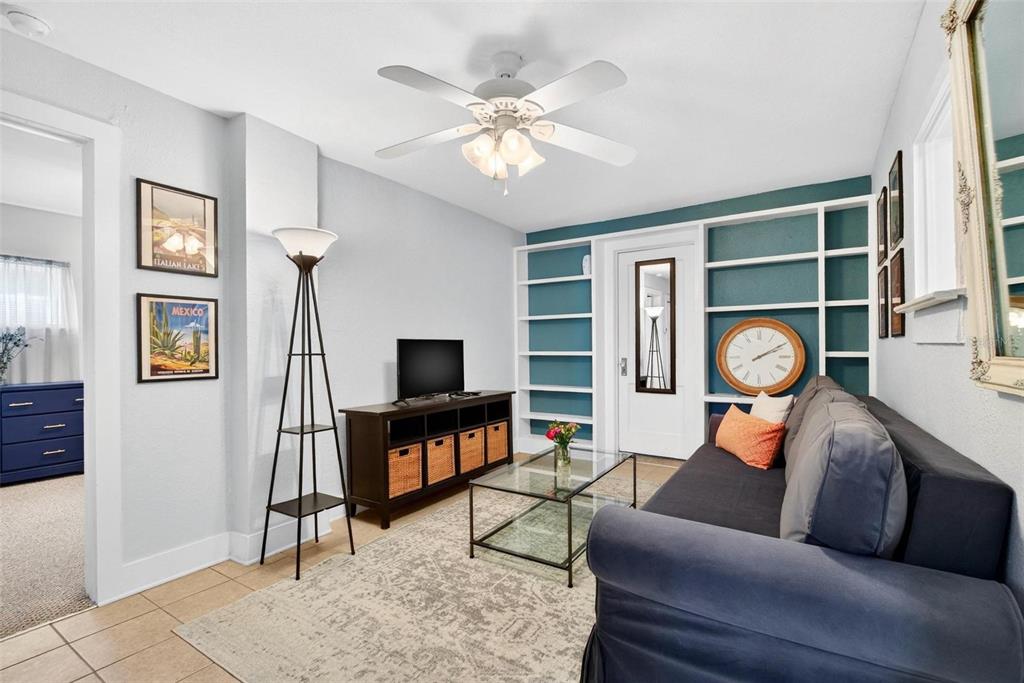 A living room features a dark sofa, a glass coffee table, and built-in teal shelving — 509 29TH AVENUE S UNIT C, ST PETERSBURG, FL