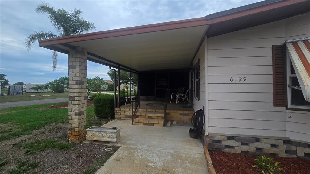A covered concrete porch with brick steps and a brick support pillar leads to a home — 6199 ORIOLE BOULEVARD, ENGLEWOOD, FL