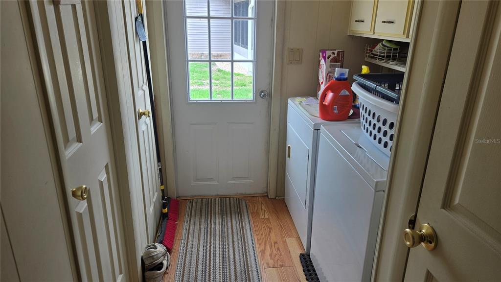 A laundry room features a white washer and dryer, wood flooring, and a glass-paneled door — 6199 ORIOLE BOULEVARD, ENGLEWOOD, FL