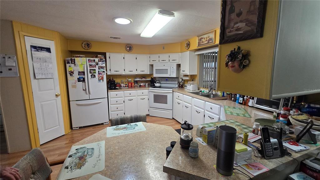 A kitchen features white cabinets, yellow walls, a central island, and white appliances — 6199 ORIOLE BOULEVARD, ENGLEWOOD, FL