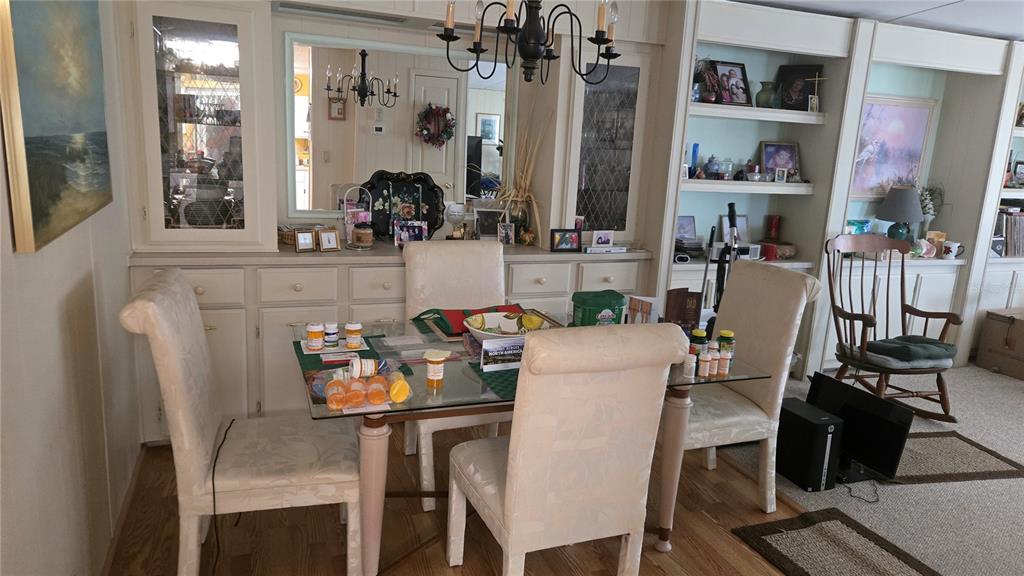 A dining room features a glass-topped table, four upholstered chairs, built-in cabinetry, and a chandelier — 6199 ORIOLE BOULEVARD, ENGLEWOOD, FL