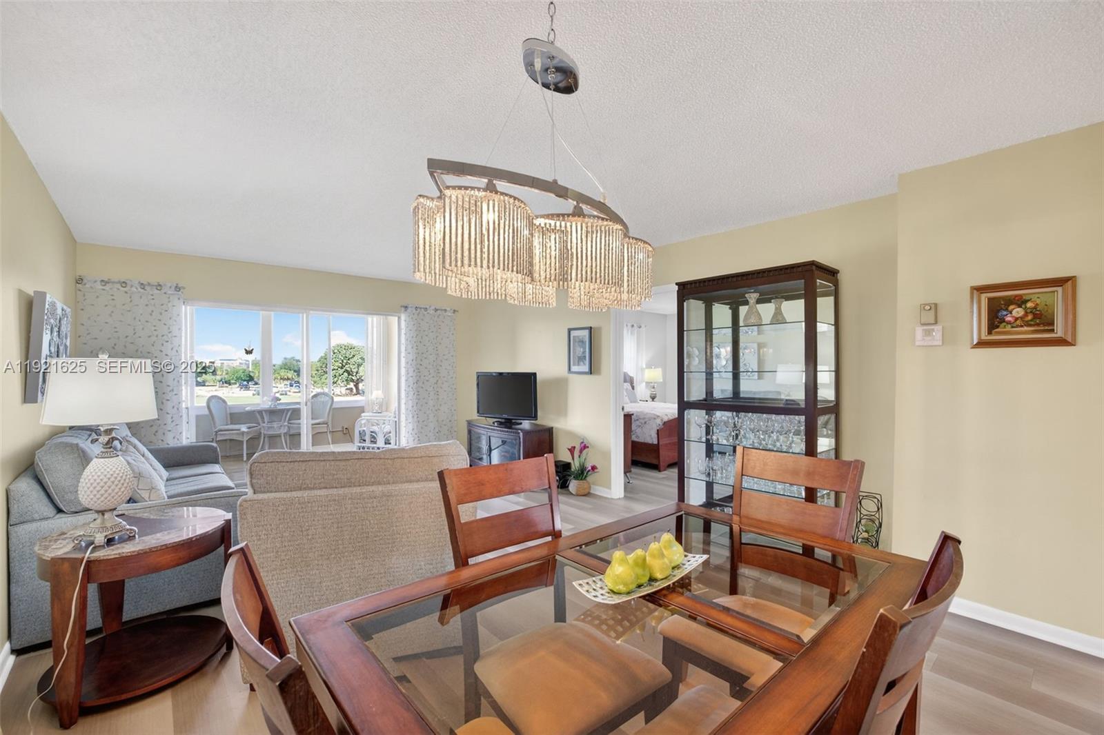 A dining area with a glass table and crystal chandelier opens into a living room — 7817 Golf Circle Dr # 301, Margate FL 33063, MARGATE, FL
