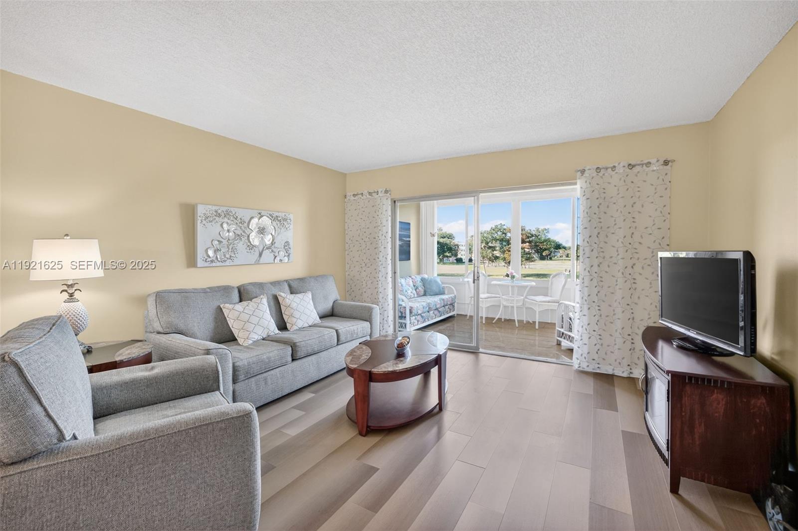 A living room features gray furniture, a wood coffee table, and a sliding door to a balcony — 7817 Golf Circle Dr # 301, Margate FL 33063, MARGATE, FL