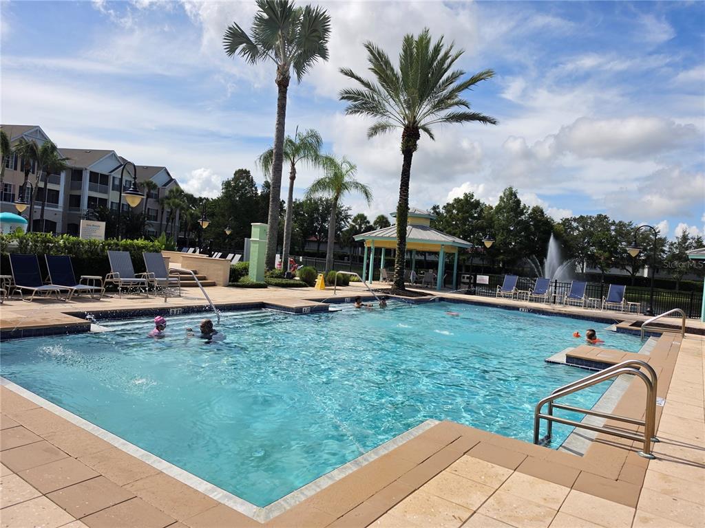 An outdoor swimming pool with lounge chairs, palm trees, and a gazebo in the background — 3016 BONFIRE BEACH DRIVE UNIT 103, KISSIMMEE, FL
