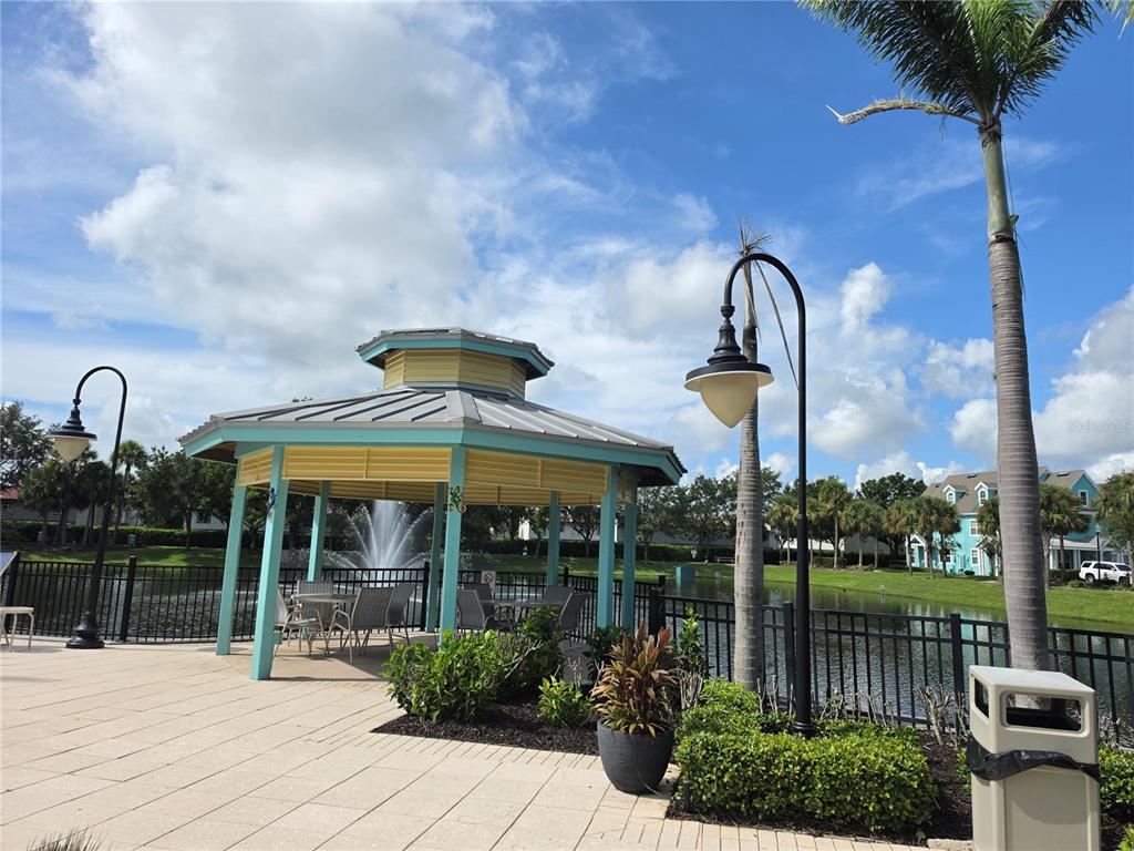 A gazebo with a metal roof sits on a paved patio overlooking a pond — 3016 BONFIRE BEACH DRIVE UNIT 103, KISSIMMEE, FL
