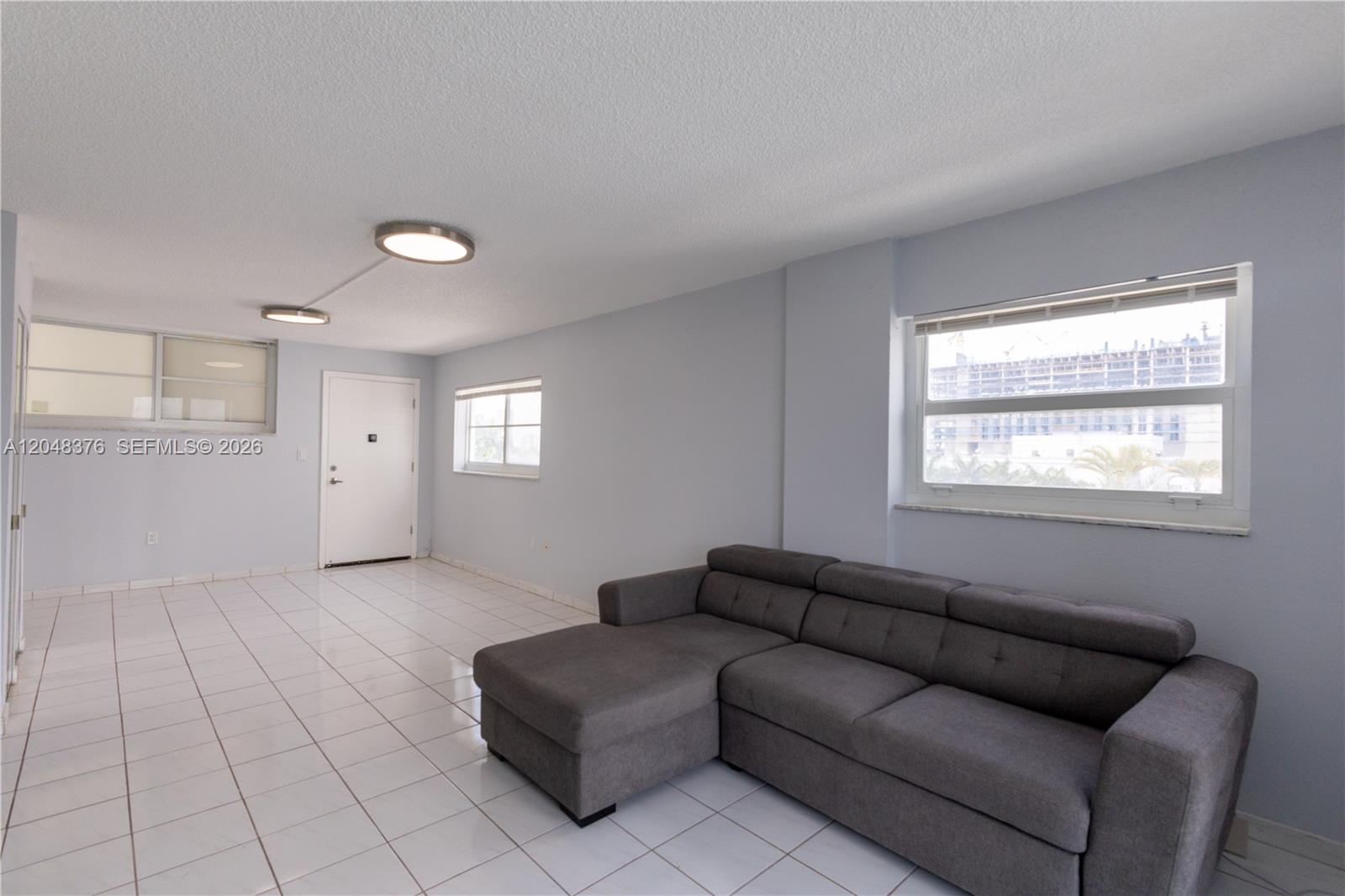 A living room features a gray sectional sofa, white tile floors, and two windows — 1750 James Ave # 7L, Miami Beach FL 33139, MIAMI BEACH, FL