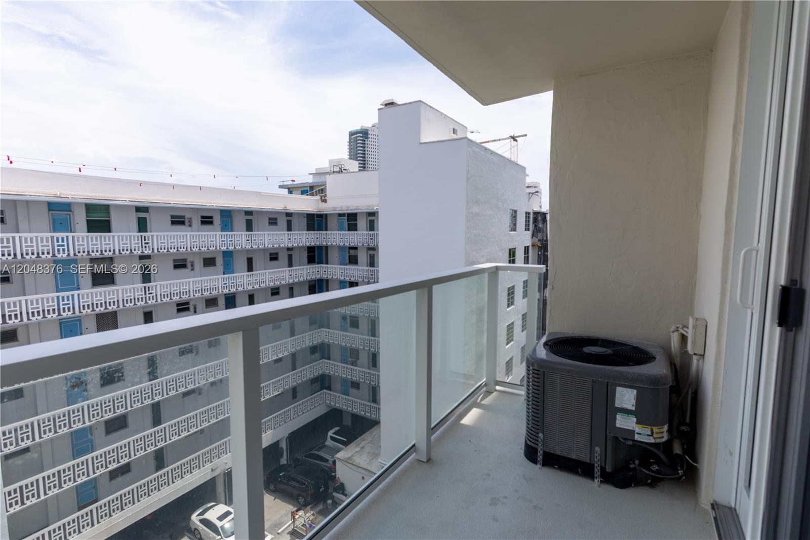 A balcony features a glass railing, a concrete floor, and an outdoor air conditioning unit — 1750 James Ave # 7L, Miami Beach FL 33139, MIAMI BEACH, FL