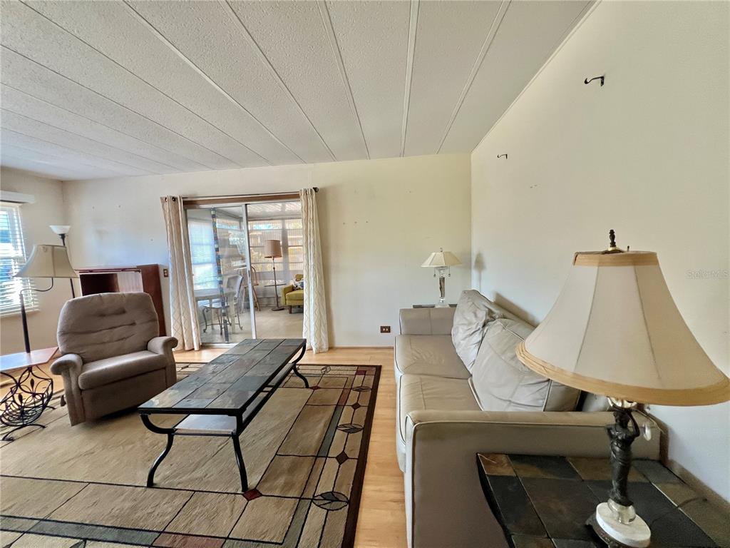 A living room features a beige sofa, a recliner, a coffee table, and a sliding door — 101 IXORA WAY, LEESBURG, FL
