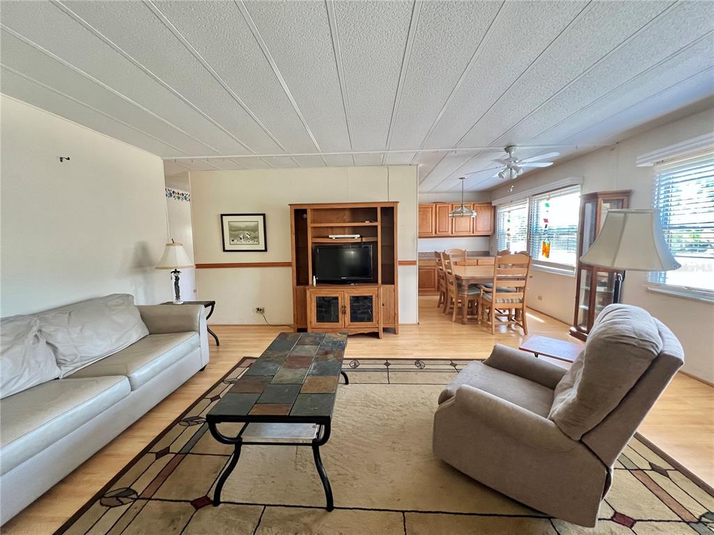 A living room with a sofa, armchair, coffee table, and an adjacent dining area — 101 IXORA WAY, LEESBURG, FL