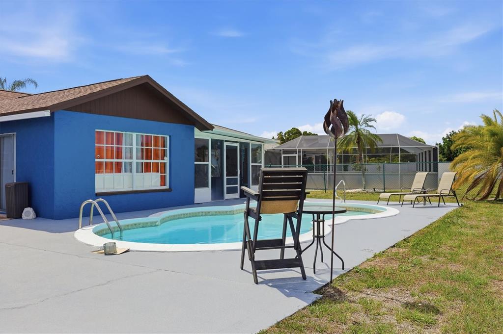 A blue house exterior features a swimming pool, a patio, and lounge chairs — 6358 GRANGER ROAD, PORT CHARLOTTE, FL