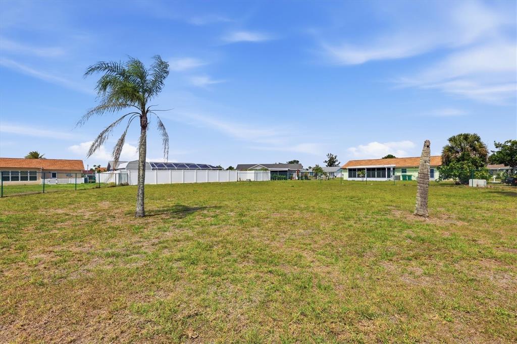 A grassy, vacant residential lot features two palm trees under a bright blue sky — 6358 GRANGER ROAD, PORT CHARLOTTE, FL