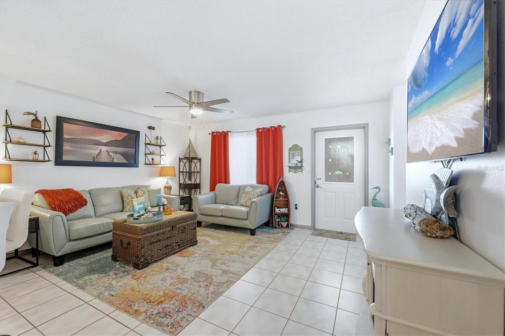 A living room features light-colored tile floors, a gray sofa set, and orange curtains — 6358 GRANGER ROAD, PORT CHARLOTTE, FL