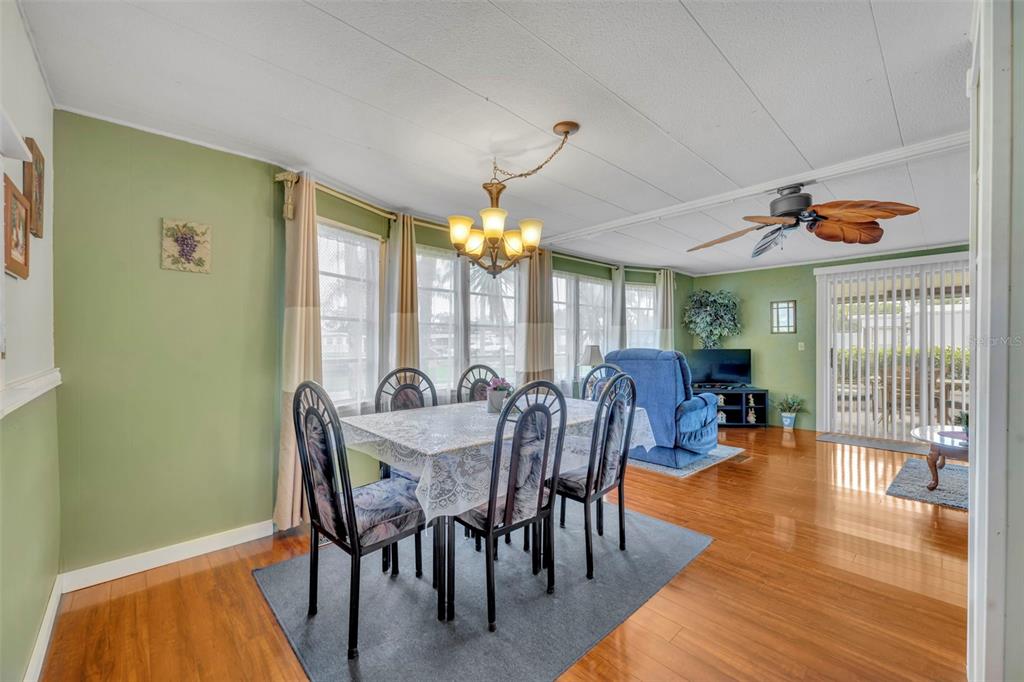 A dining area with a table and chairs sits on a rug near a living space — 104 DIAMOND HEAD DRIVE, LEESBURG, FL