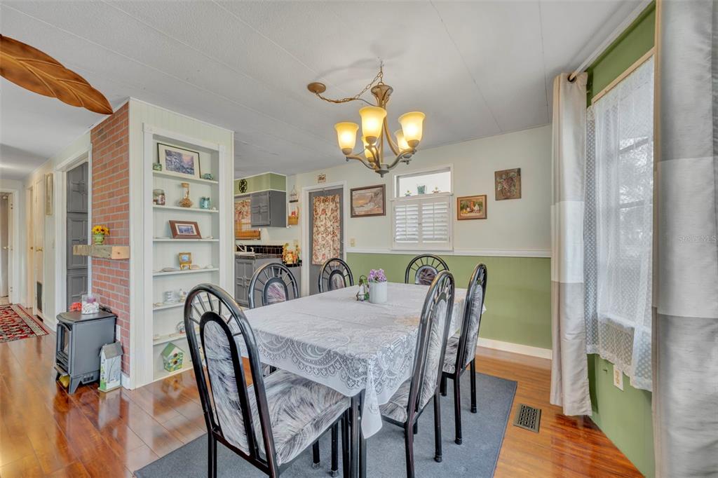 A dining room features a table with six chairs, a chandelier, and green wainscoting — 104 DIAMOND HEAD DRIVE, LEESBURG, FL