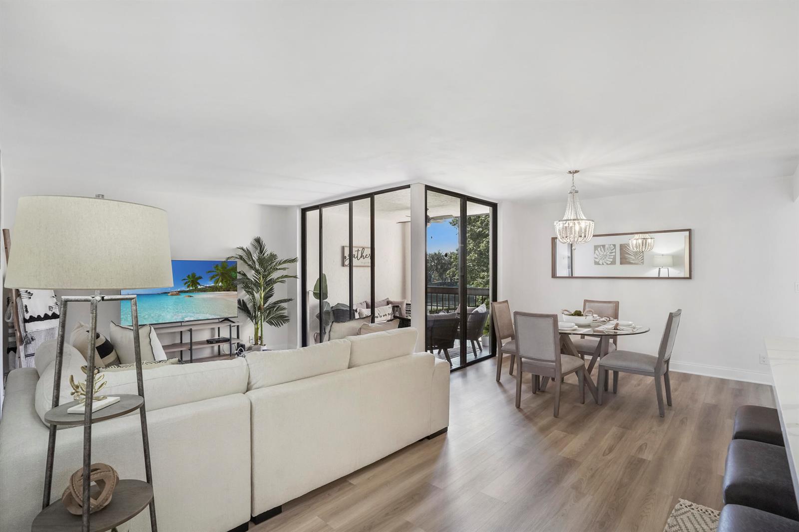 A living and dining area features light wood flooring, a white sectional, and a glass-enclosed balcony — 750 Egret Circle # 6304, Delray Beach FL 33444, DELRAY BEACH, FL