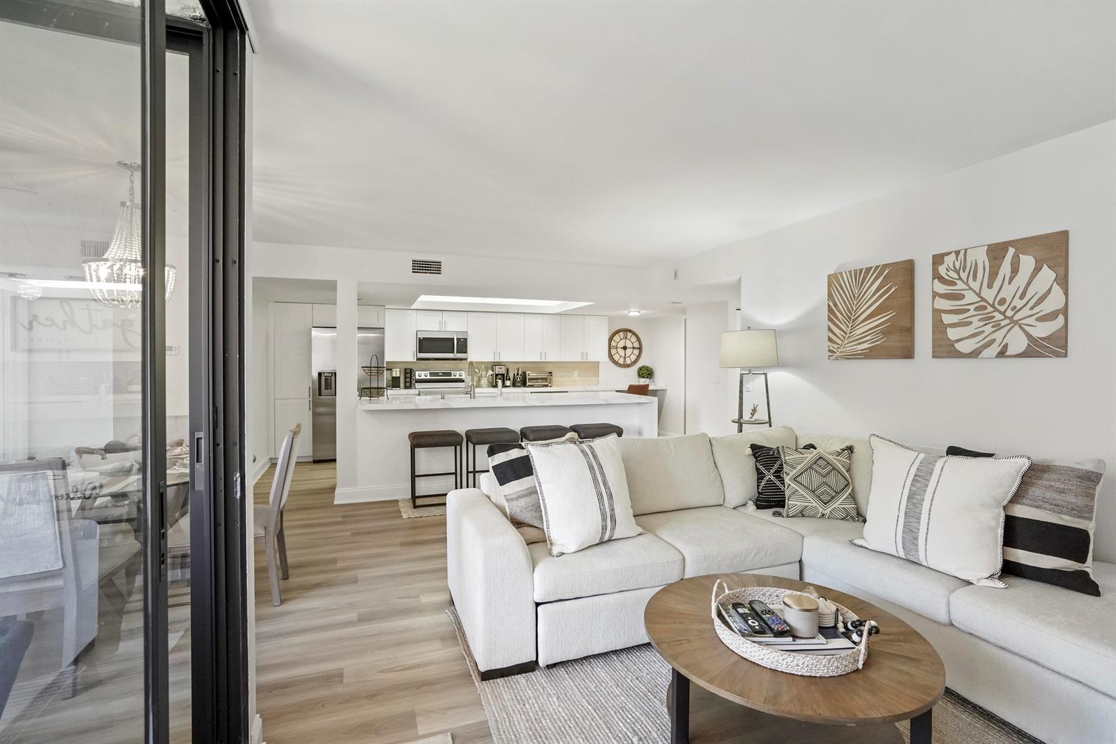 A bright living room with a sectional sofa opens to a white kitchen with bar seating — 750 Egret Circle # 6304, Delray Beach FL 33444, DELRAY BEACH, FL