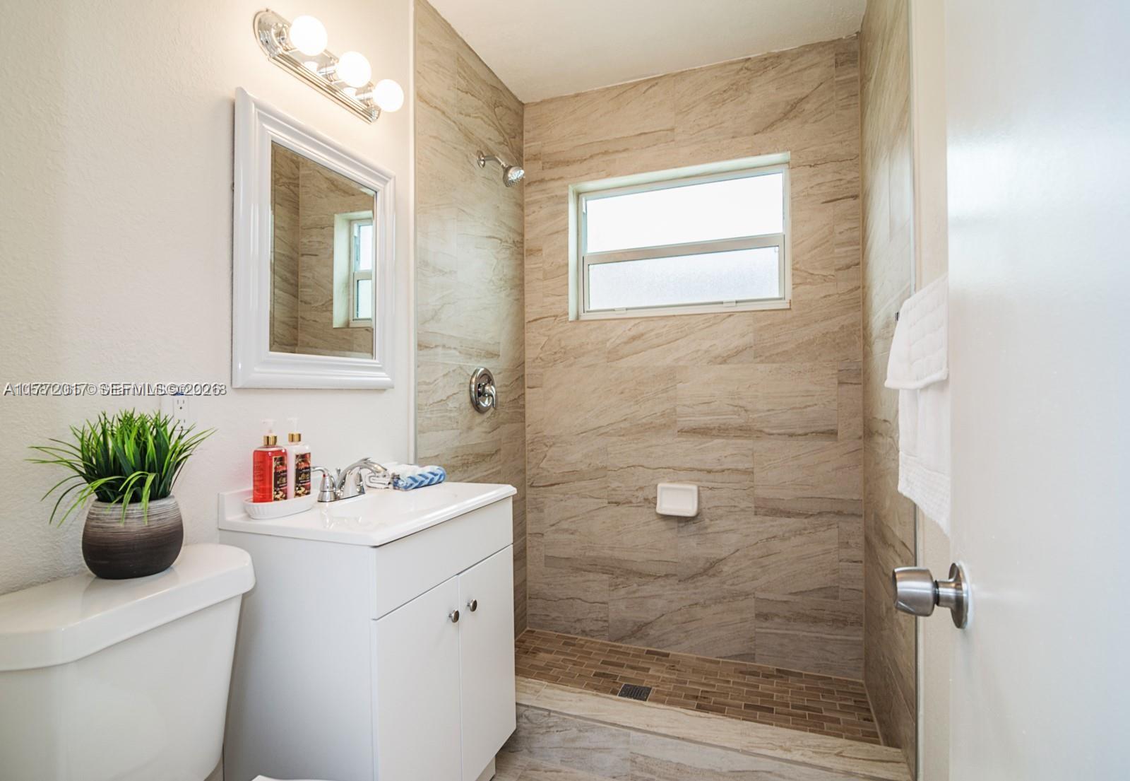 A bathroom features a white vanity, a toilet, and a tiled walk-in shower — 2542 Fillmore St, Hollywood FL 33020, HOLLYWOOD, FL