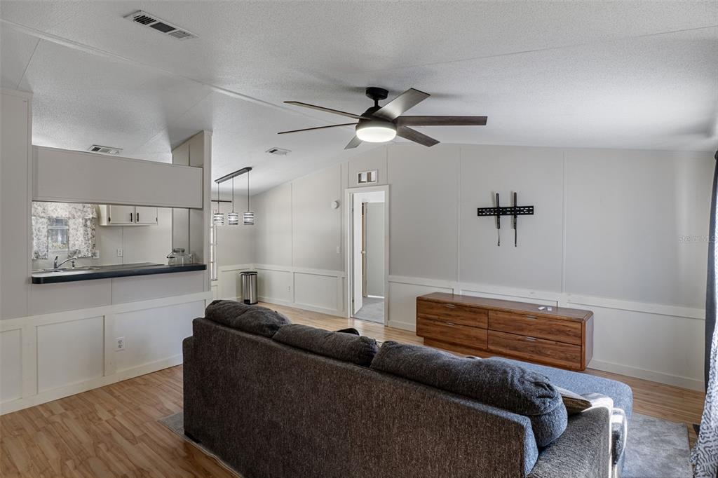 A living room with a gray sofa, wood-look flooring, and a ceiling fan — 4350 S SONGBIRD DRIVE, LECANTO, FL