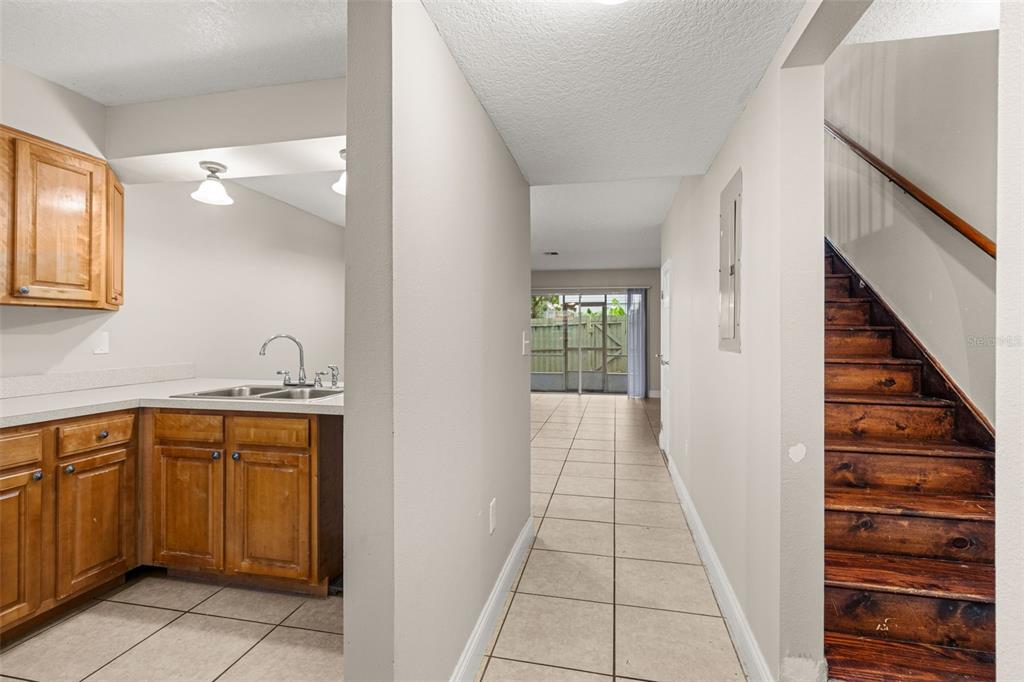 A view from a kitchen into a hallway with tile floors and a wooden staircase — 1824 AMBERLY AVENUE UNIT T8, ORLANDO, FL