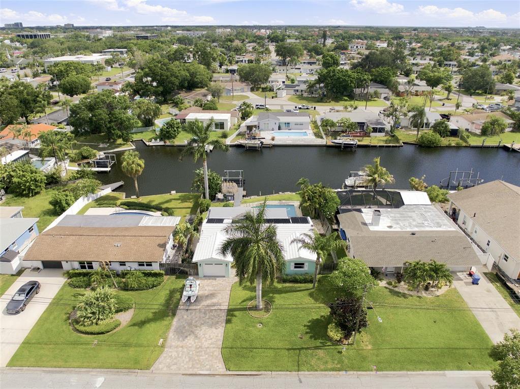 An aerial view shows three waterfront houses with pools and boat docks along a canal — 101 92ND AVENUE N, ST PETERSBURG, FL